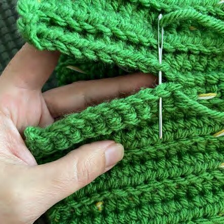 Yarn needle joining the ribbed beanie side seam