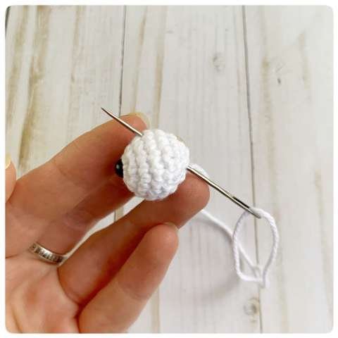 Original crochet frog tutorial photo 25, showing the eyes being assembled and sewn onto the frog.