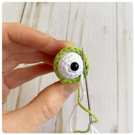 Original crochet frog tutorial photo 26, showing the eyes being assembled and sewn onto the frog.