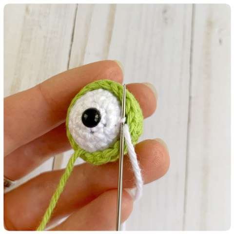 Original crochet frog tutorial photo 27, showing the eyes being assembled and sewn onto the frog.