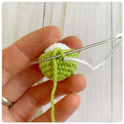 Original crochet frog tutorial photo 29, showing the eyes being assembled and sewn onto the frog.