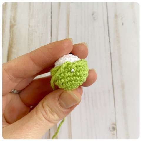Original crochet frog tutorial photo 30, showing the eyes being assembled and sewn onto the frog.