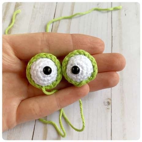Original crochet frog tutorial photo 31, showing the eyes being assembled and sewn onto the frog.