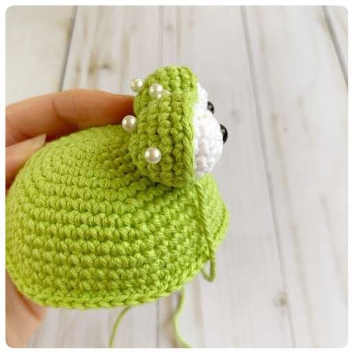 Original crochet frog tutorial photo 32, showing the eyes being assembled and sewn onto the frog.