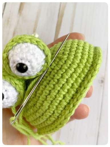 Original crochet frog tutorial photo 34, showing the eyes being assembled and sewn onto the frog.