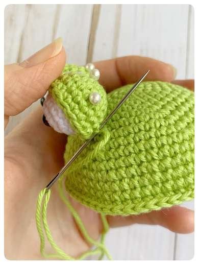 Original crochet frog tutorial photo 35, showing the eyes being assembled and sewn onto the frog.