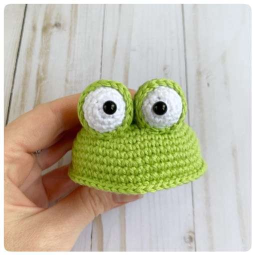 Original crochet frog tutorial photo 37, showing the eyes being assembled and sewn onto the frog.