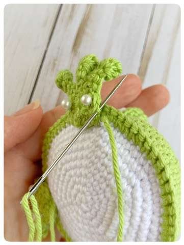 Original crochet frog tutorial photo 41, showing the front paws being positioned and sewn on.