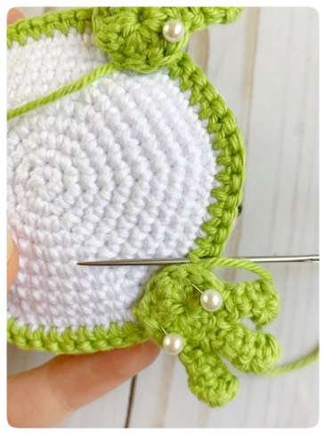 Original crochet frog tutorial photo 43, showing the front paws being positioned and sewn on.