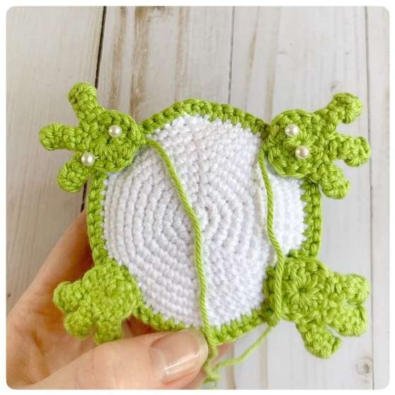 Original crochet frog tutorial photo 45, showing the back paws being positioned and sewn on.