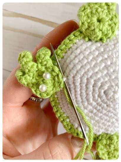 Original crochet frog tutorial photo 48, showing the back paws being positioned and sewn on.